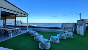 Une terrasse avec un revêtement de gazon synthétique, des sièges d’extérieur et une vue sur la mer.