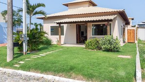 A house with a tiled roof, a front porch, and a well-maintained lawn.