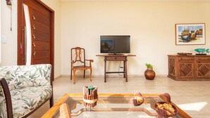A living room with a sofa, a coffee table with snacks, a TV, a wooden cabinet, and a painting on the wall.