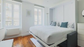 Een slaapkamer met een bed, bureau en raam.
