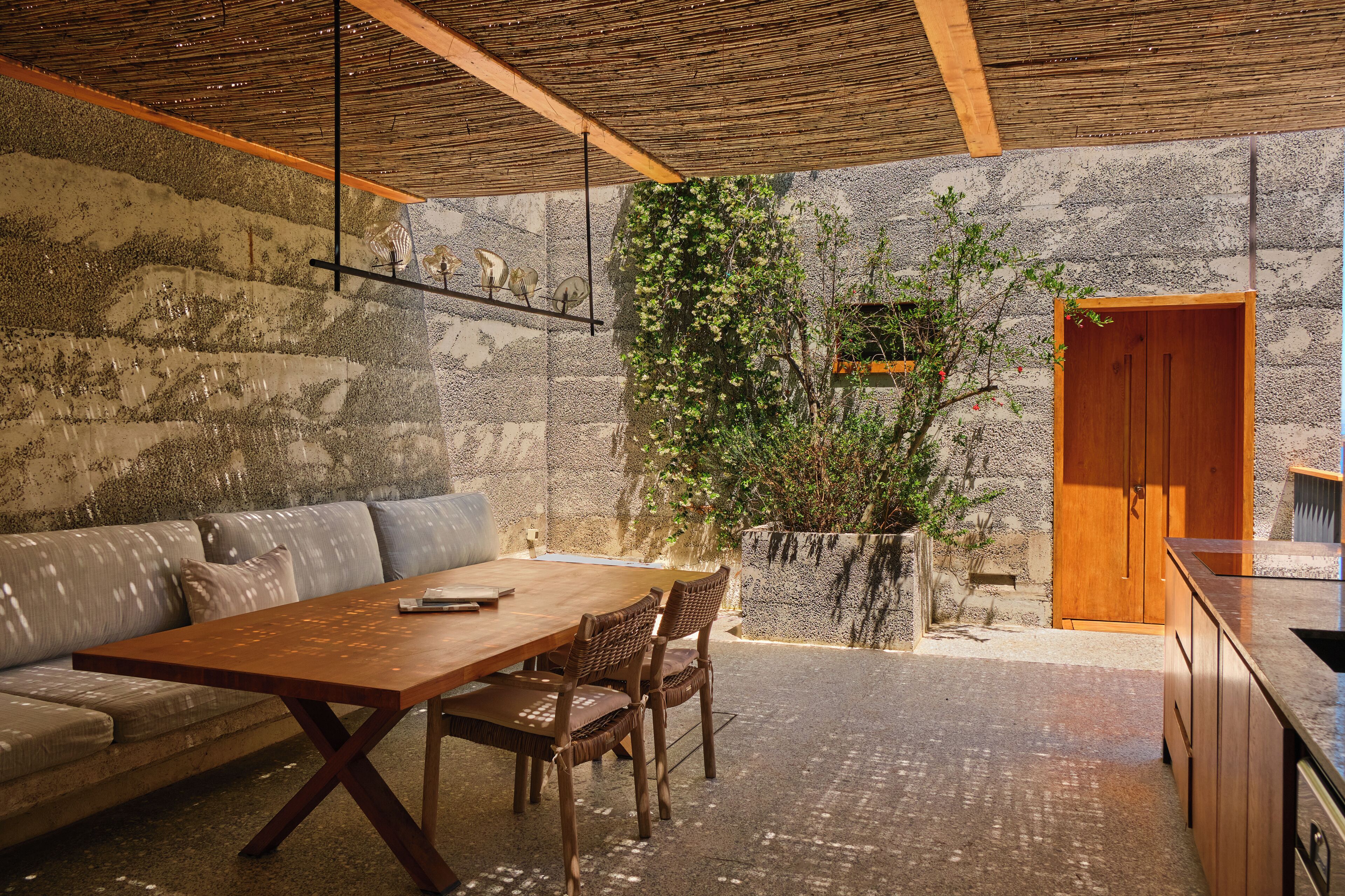 A modern kitchen with a wooden table and chairs, a stone wall, and a wooden door.