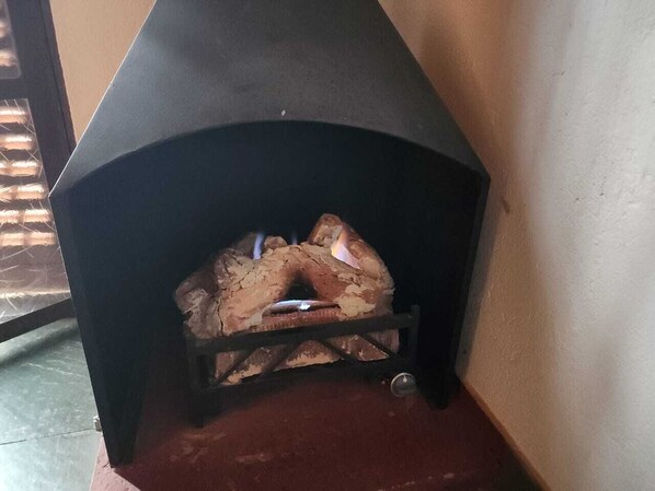 A fireplace with logs burning inside. - Pousada Cachyto de Cielo (Campos do Jordão)