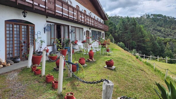 A traditional chalet-style building with a sloped roof, large windows, and a balcony. - Pousada Cachyto de Cielo (Campos do Jordão)