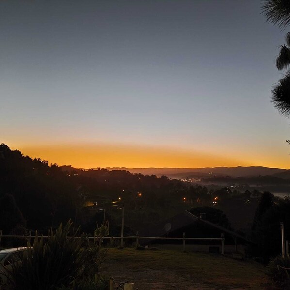 A sunset view from a hilltop with distant city lights. - Pousada Cachyto de Cielo (Campos do Jordão)