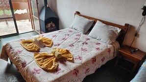 A bed with floral bedding, two yellow towels, a wooden headboard, and a nightstand with a phone. - Pousada Cachyto de Cielo (Campos do Jordão)