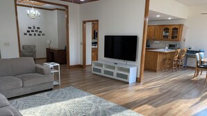 A modern living room with a large flat-screen TV, a sofa, a coffee table, and a patterned rug. - Peaceful 3-bedroom accessible ranch home with AC, WiFi in Eastside Olathe. (Olathe)