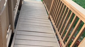A wooden deck with a railing, leading to a grassy yard. - Peaceful 3-bedroom accessible ranch home with AC, WiFi in Eastside Olathe. (Olathe)