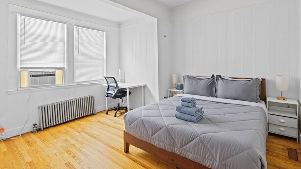 A bedroom with a bed, a desk, and a chair.