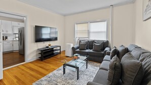A modern living room with a flat-screen TV, grey sofa, and a coffee table.