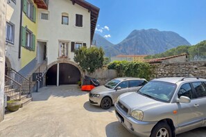 Un bâtiment avec un garage, des voitures garées et une montagne en arrière-plan.