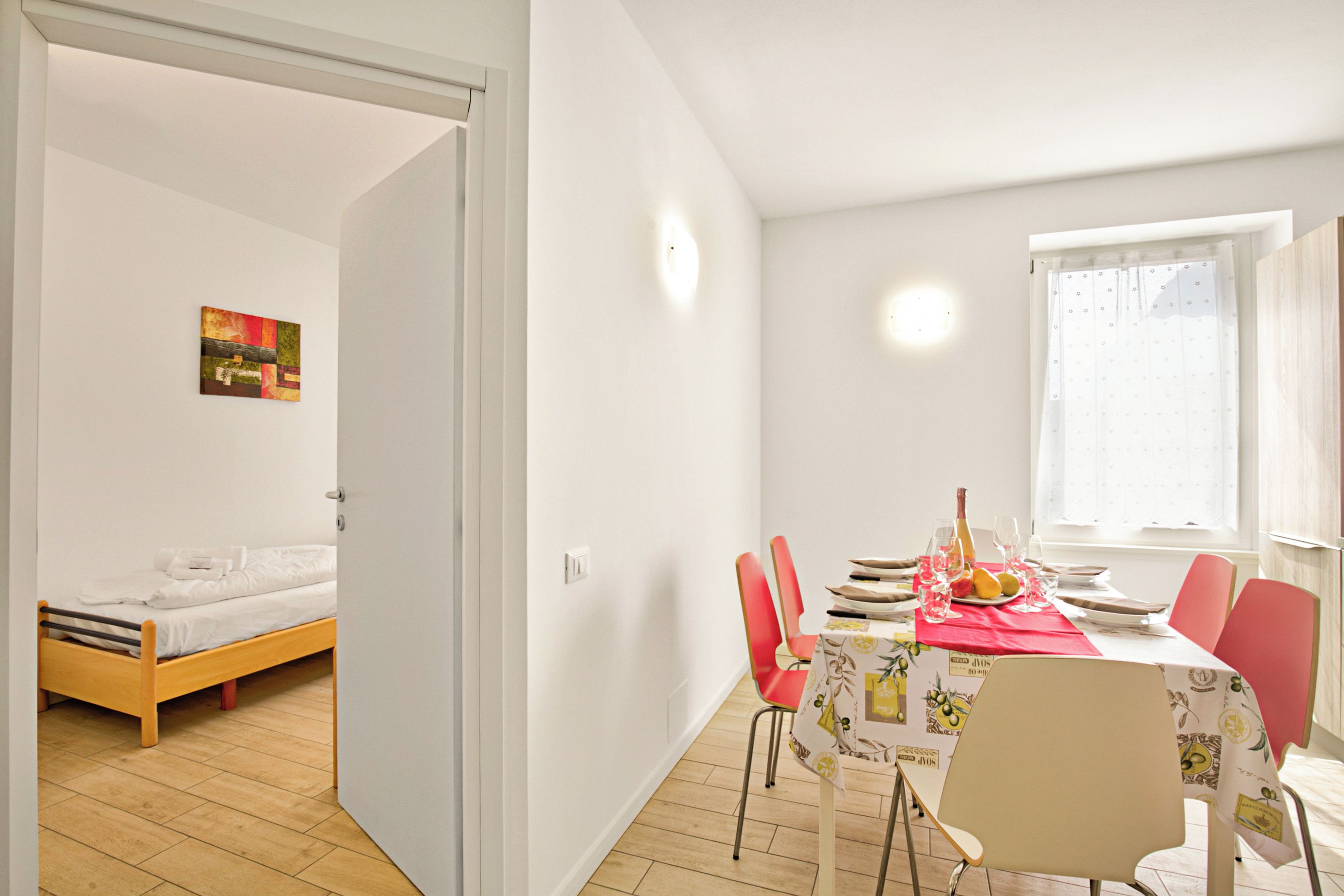 A room with a bed, a dining table with chairs, and a window.