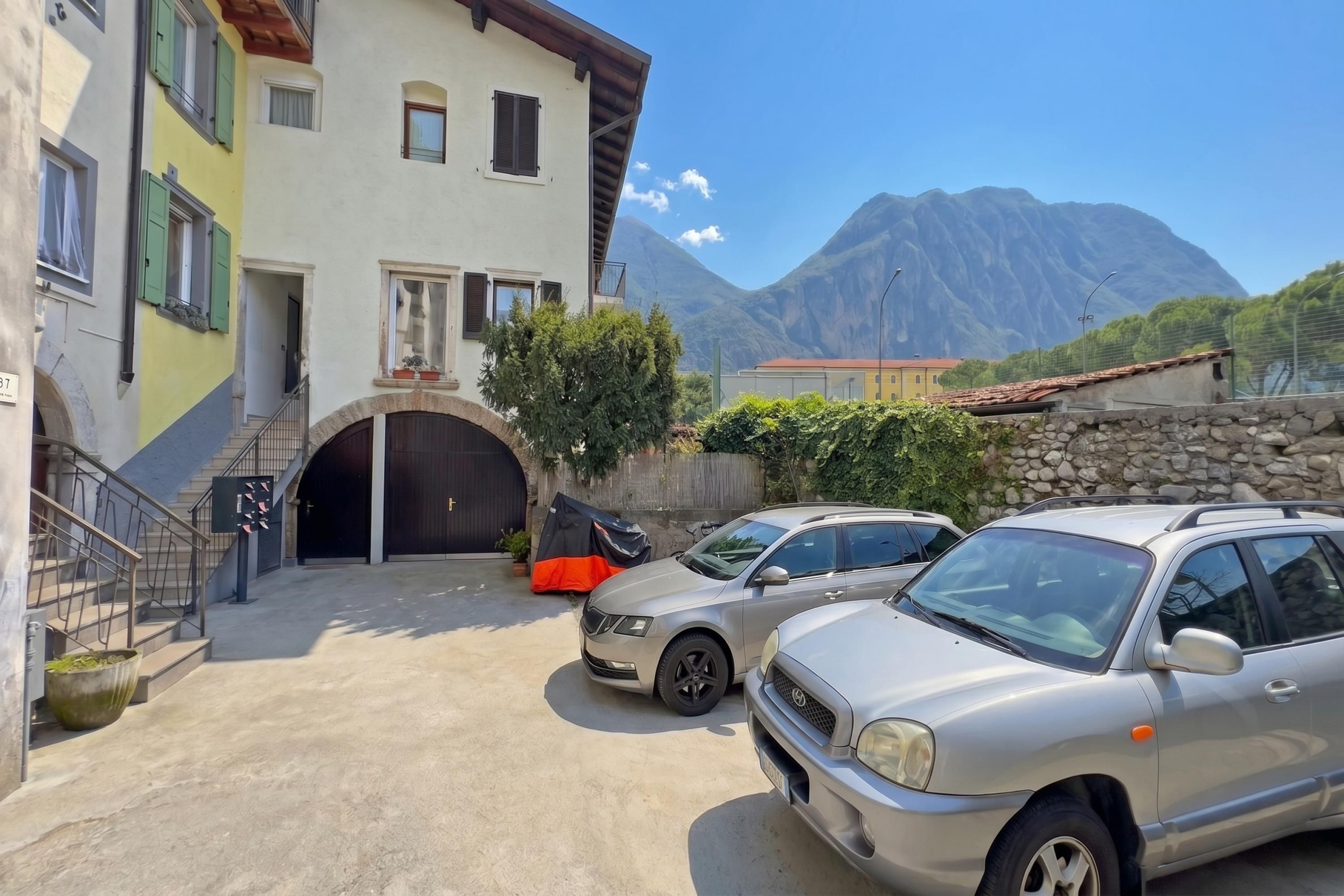 A building with a garage, parked cars, and a mountain backdrop.