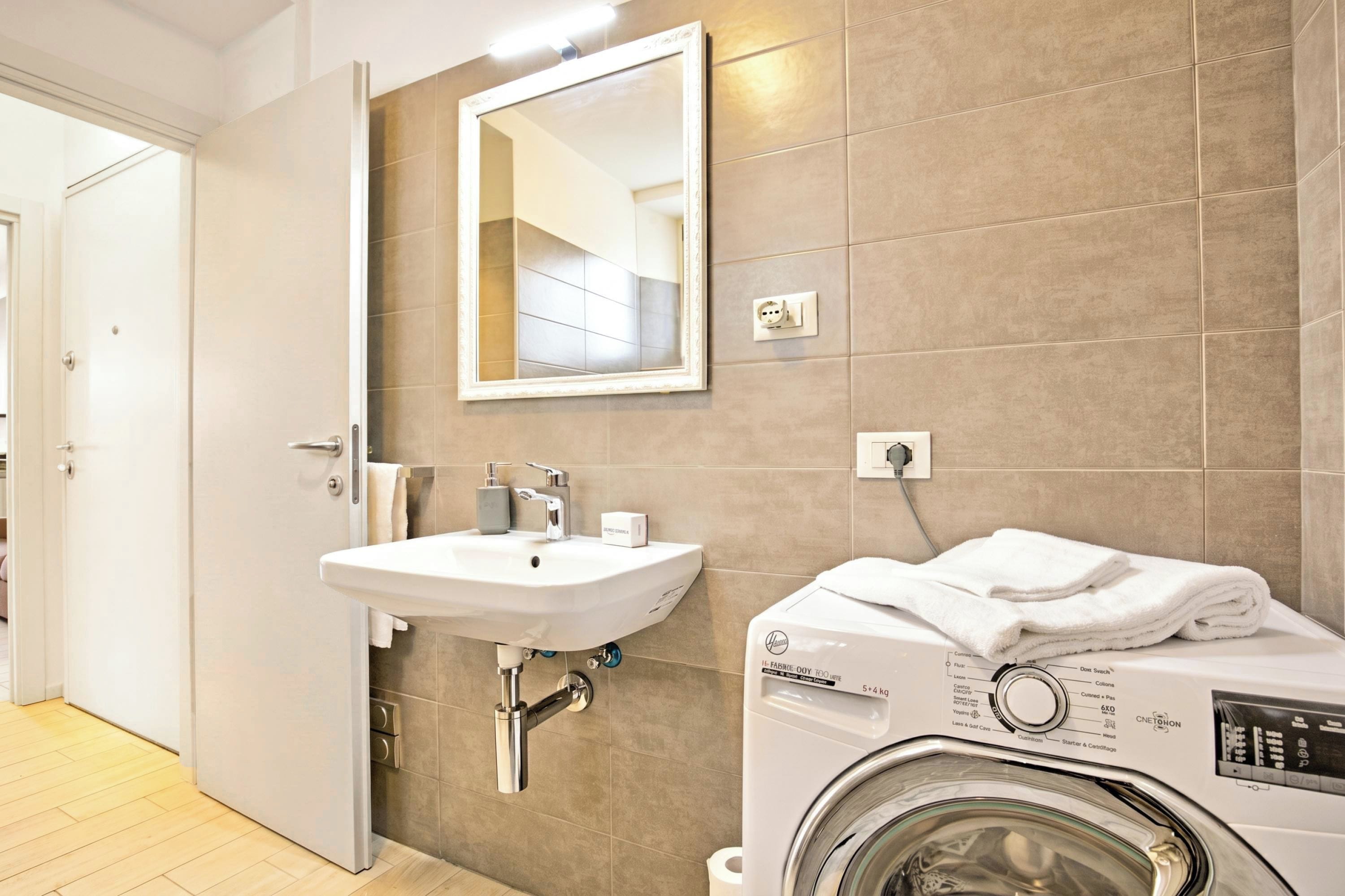Une salle de bain moderne équipée d’un lavabo, d’un miroir et d’un lave-linge.