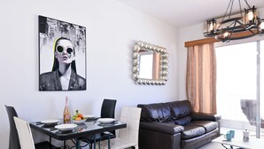 Zona de menjador amb una taula preparada per a dues persones, un sofà de cuir marró i un mirall decoratiu.