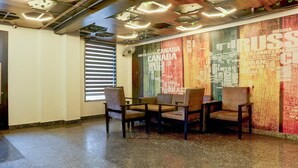 A room with a large wall mural, a window with blinds, and a seating area with chairs and a table.