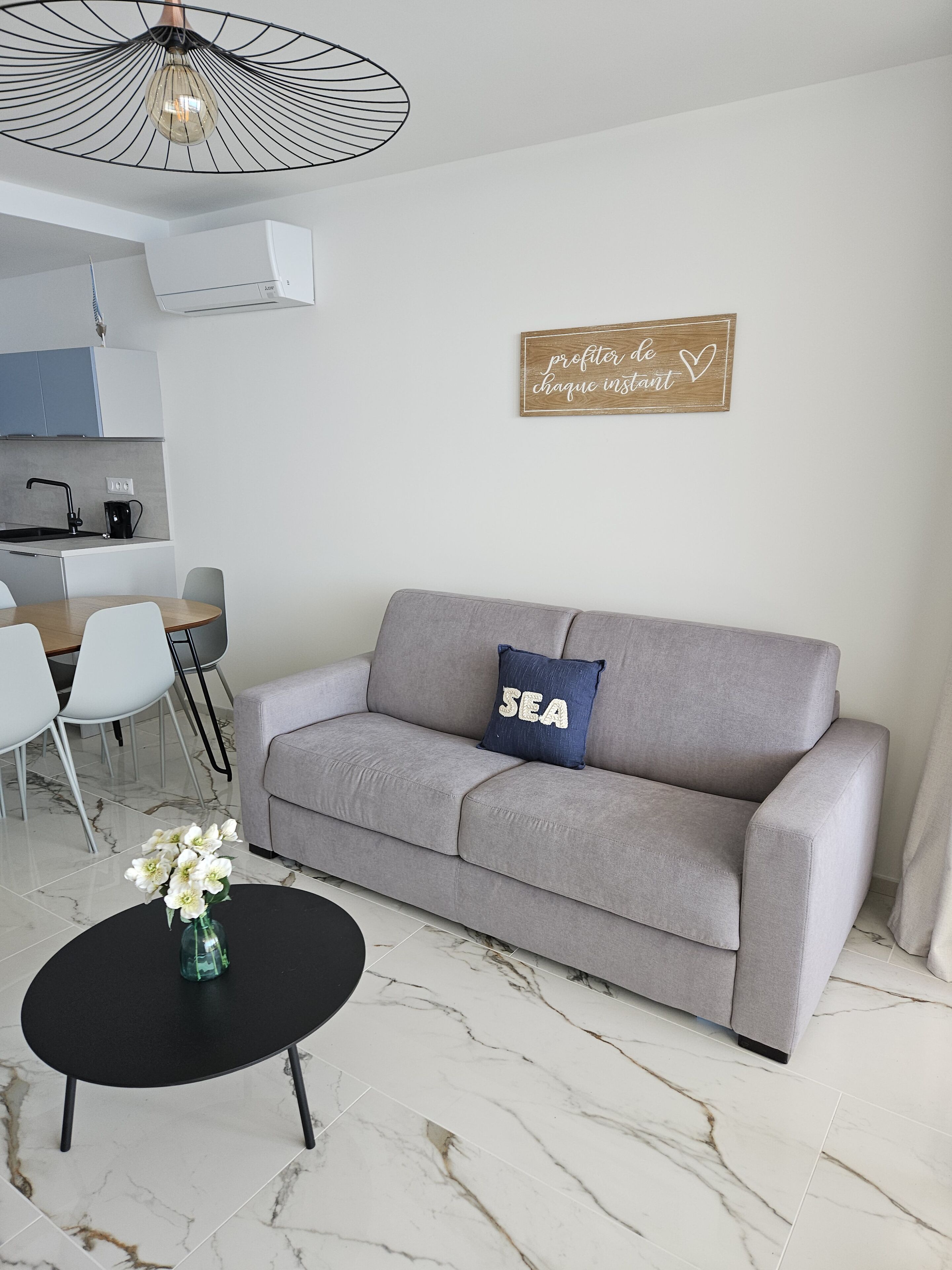 A modern living room with a grey sofa, a black coffee table, and a vase with flowers.