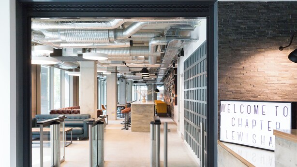 An interior corridor with a reception desk, seating area, and a view of the outside. - Chapter Lewisham Student Only Cozy Stay (London)
