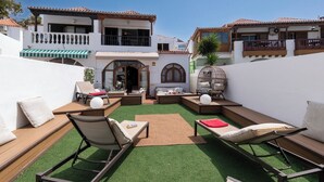 A courtyard with outdoor seating, a birdcage, and a building with a tiled roof. - Villa Tricia 6 Bedroom Las Americas (Arona)