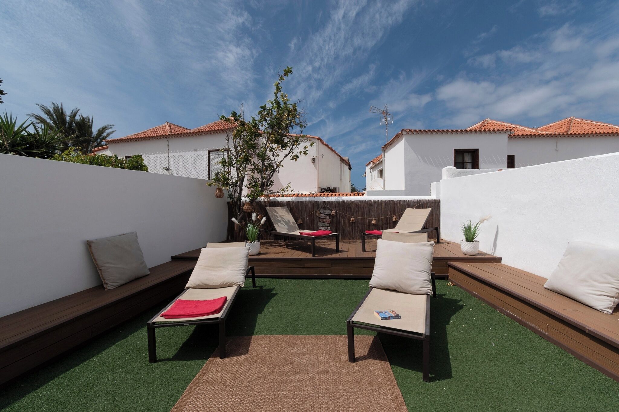 Eine Dachterrasse mit zwei Liegestühlen, einem kleinen Tisch und einer Hängematte.