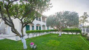 A well-maintained garden with neatly trimmed hedges and a variety of trees. - Stavros Apartments Gouvia Marina (Corfu)