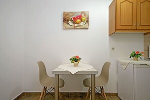 Un petit coin repas comprenant une table, deux chaises, un tableau au mur et un meuble.