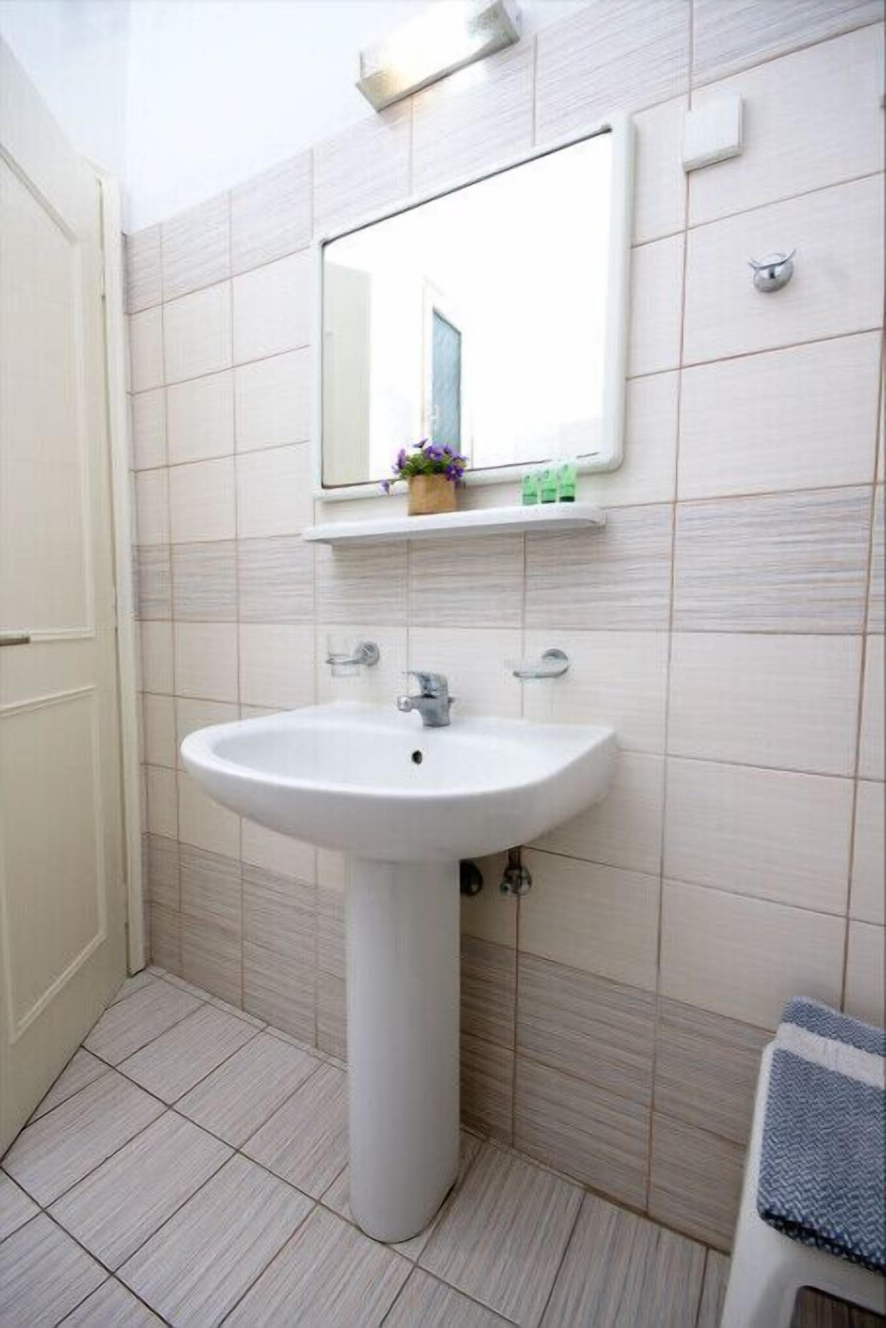 A bathroom with a pedestal sink, a mirror, and a towel rack.