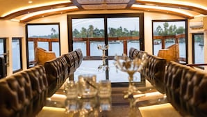Un comedor con asientos de cuero, una mesa de vidrio y vista al agua.