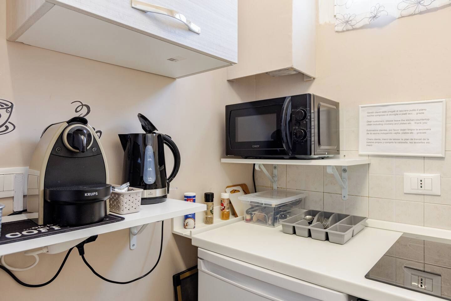 Eine Küchenzeile mit Kaffeemaschine, Wasserkocher, Mikrowelle und kleinem Kühlschrank.