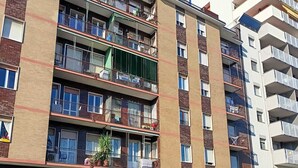 Un edificio residencial de varios pisos con balcones, entrada a nivel de la calle y puerta de garaje visible.