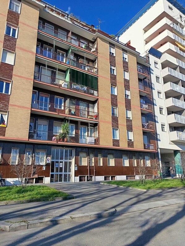 Een meerlaags woongebouw met balkons, een inkom aan de begane grond en een zichtbare garagepoort.