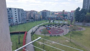 Un parque con juegos infantiles, una pista circular y edificios circundantes.