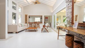 A spacious living room with a high ceiling, a large mirror, a sofa, a coffee table, and a dining table.