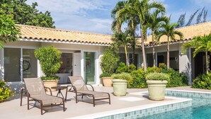 A poolside area with lounge chairs, potted plants, and a tiled pool.