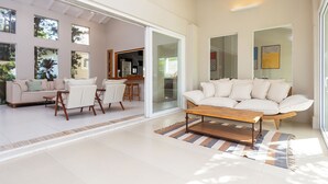 A spacious living area with a white sofa, a wooden coffee table, and a striped rug.
