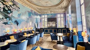 Un bar avec des sièges bleus, une fresque au plafond et un plancher en bois.