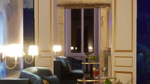Un espace de détente moderne avec des canapés, des tables rondes et des lampes fixées au mur.