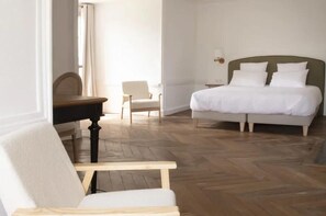 Een slaapkamer met een bed, een stoel, een bureau en een lamp.