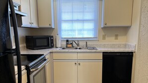 A compact kitchen with a microwave, oven, sink, and dishwasher. - Home away from home (Conway)