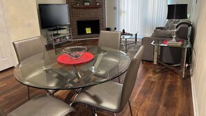 A modern living room with a glass dining table, leather chairs, a flat-screen TV, a fireplace, and a sofa. - Home away from home (Conway)