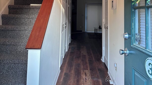 A hallway with a wooden staircase, a chandelier, and a door with a number plate. - Home away from home (Conway)