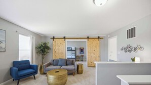 A modern living room with a blue sofa, a round coffee table, and a grey couch. - Ark & Creation Retreat For 12! (Walton)