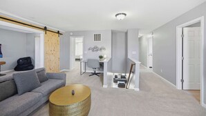 A modern living room with a grey sofa, a coffee table, and a sliding door. - Ark & Creation Retreat For 12! (Walton)