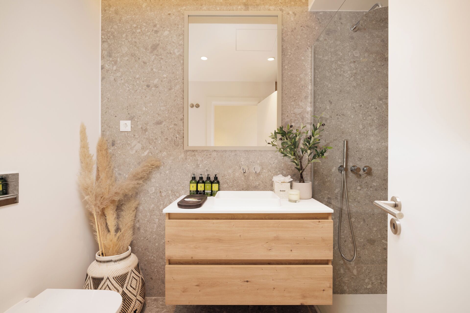A modern bathroom with a wooden vanity, a large mirror, and a shower area.
