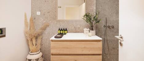 Een moderne badkamer met een houten wastafelmeubel, een grote spiegel en een douchehoek.