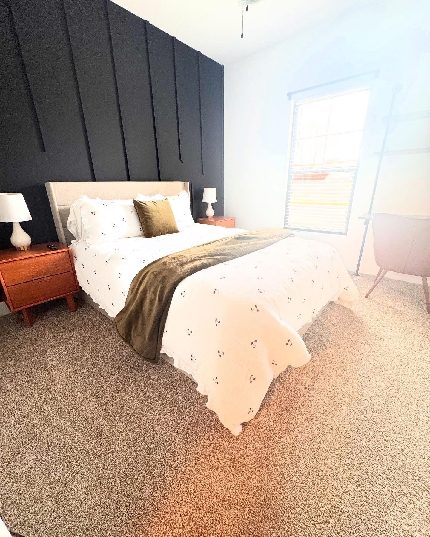 A bedroom with a bed, two bedside tables, a window, and a chair.