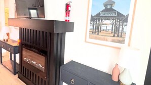 A modern living room with a fireplace, a television, and a framed picture on the wall. - The Adelyn, where comfort meets convenience (Jeffersonville)
