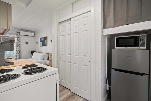 A compact kitchen with a stove, microwave, and refrigerator. - Chic Studio Near Franklin Park + Downtown (Columbus)