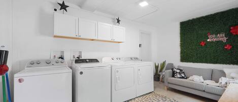 A laundry area with two washing machines, a drying machine, and a cabinet above.