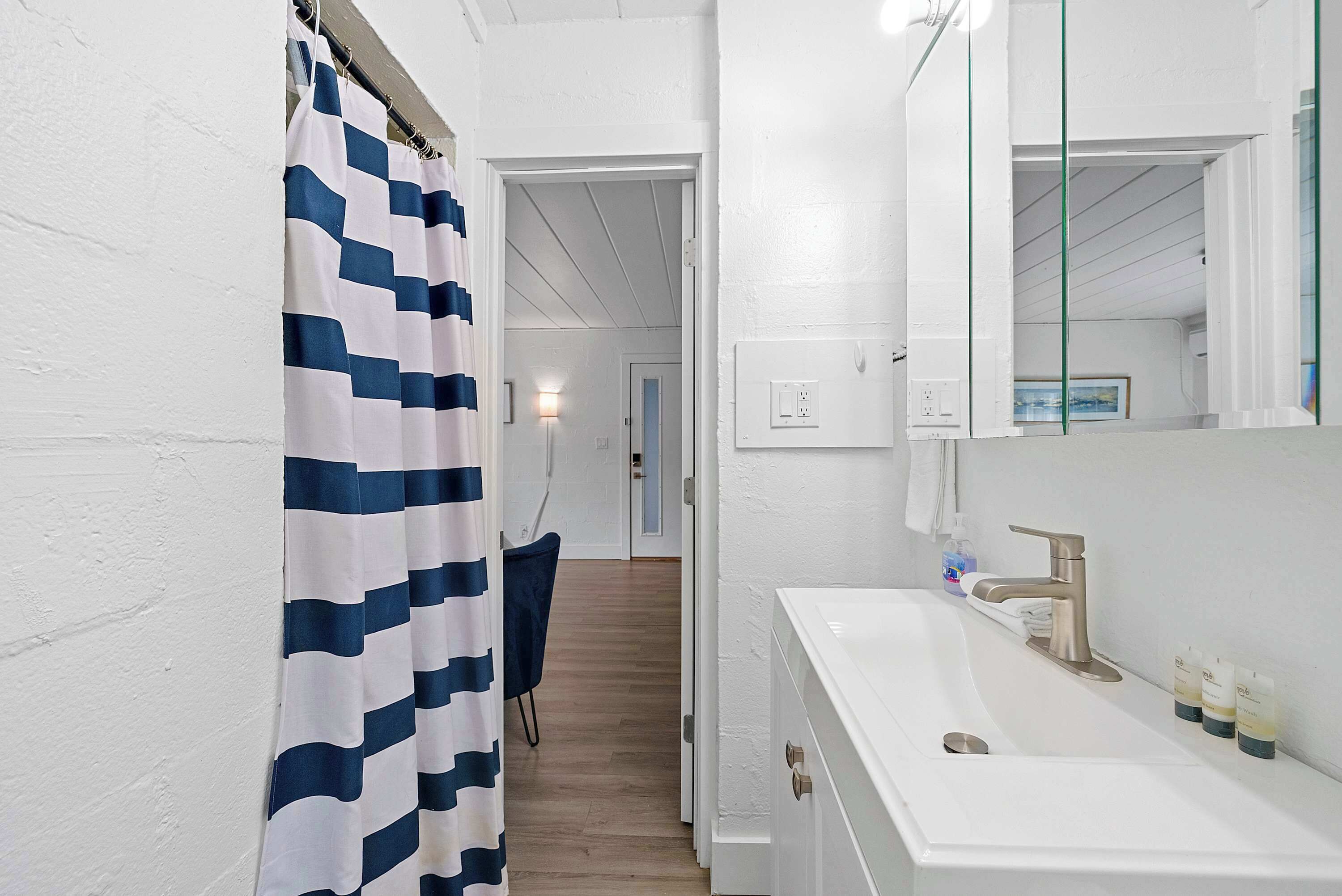 A bathroom with a white sink, a mirror, and a shower curtain.