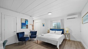 Un dormitorio con una cama, una silla, un escritorio y una ventana con cortinas.